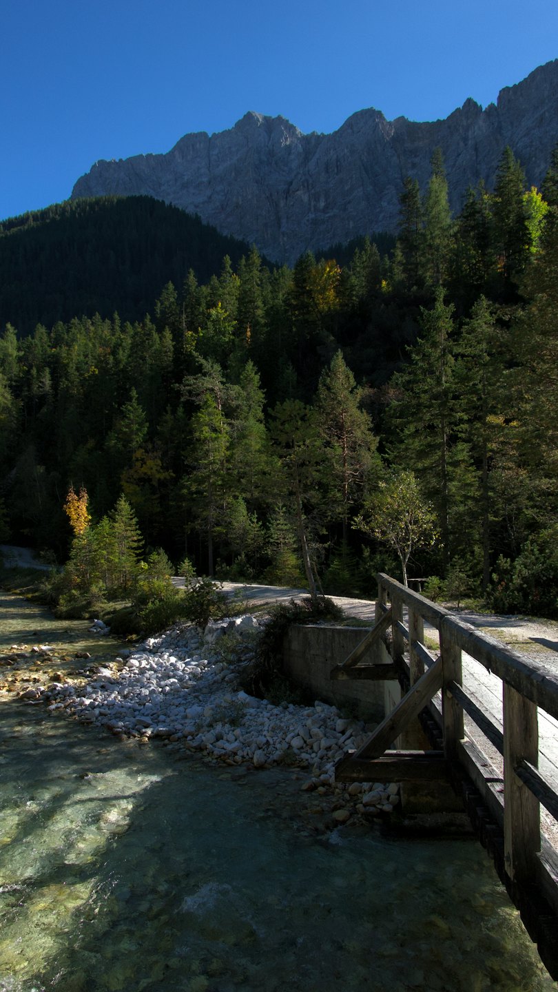 Un ponte rustico di legno attraversa un fiume di montagna roccioso.