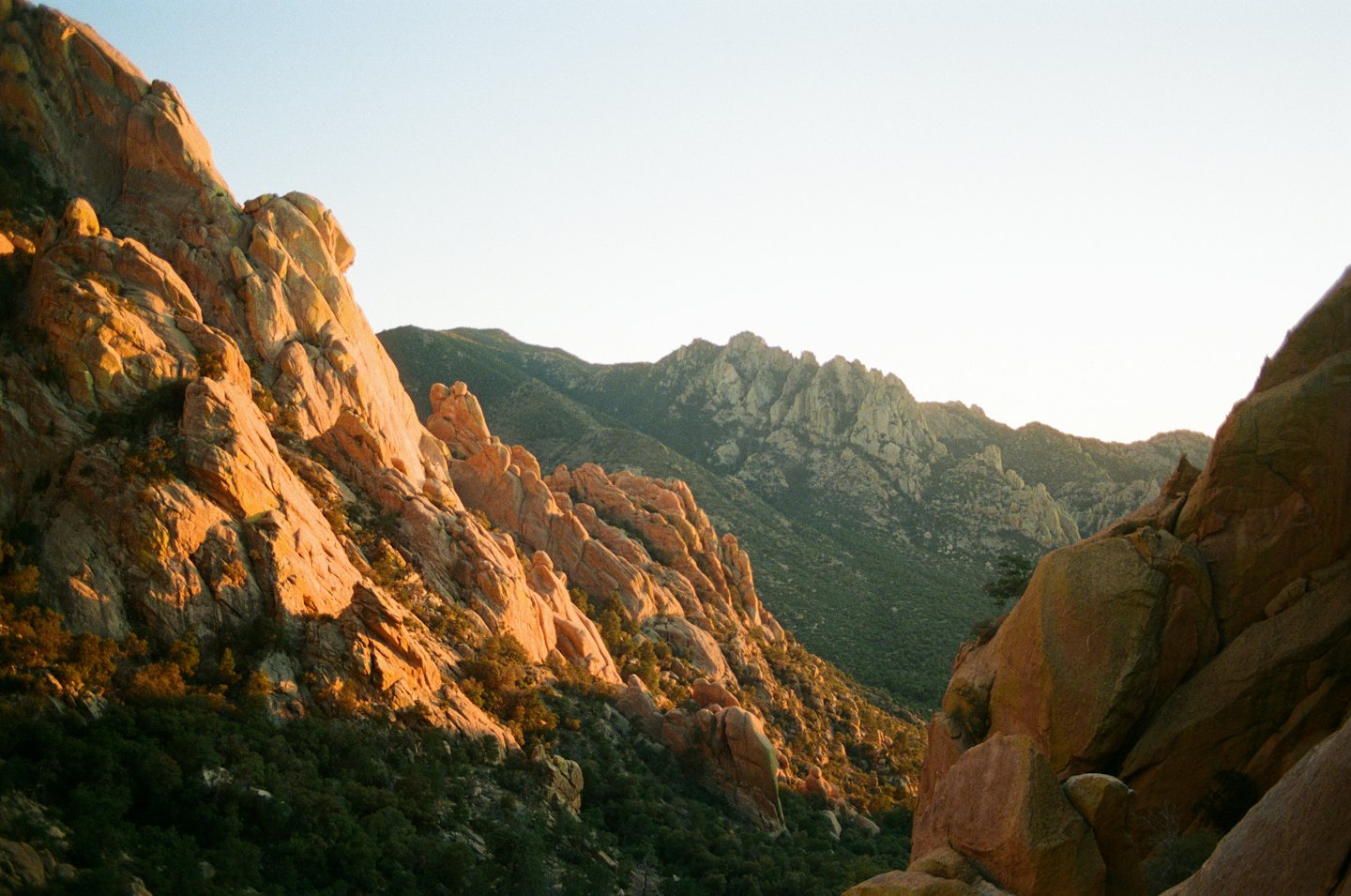 Terreno montuoso accidentato al tramonto con luce dorata sulle rocce.