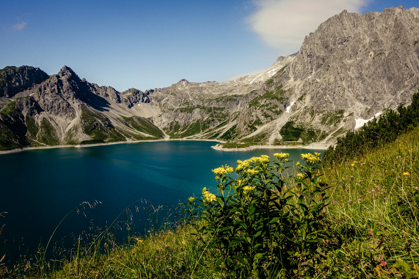 Lago alpino incastonato tra montagne frastagliate e innevate.