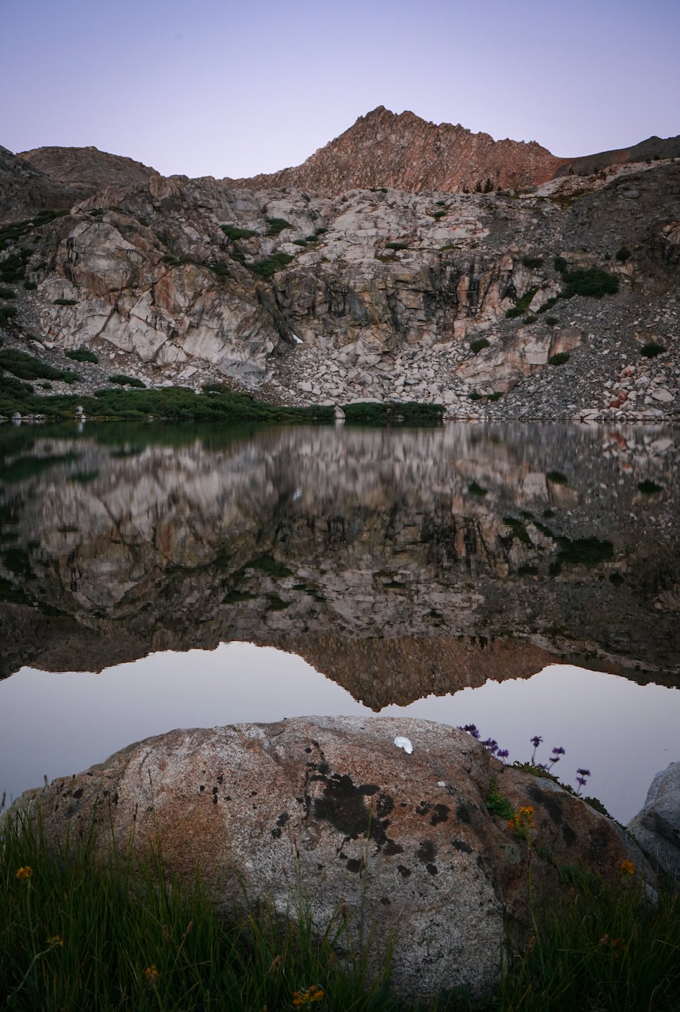 Montagne aspre si riflettono nell'acqua limpida di un lago alpino.