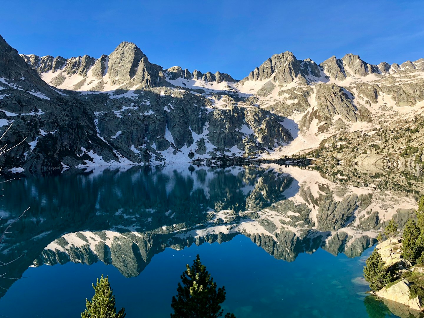 Montagne innevate si riflettono nell'acqua calma di un lago.